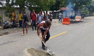 Bhabinkamtibmas-Desa-Letmafo-Timur-Gandeng-Warga-Gotong-Royong-Perbaiki-Jalan-Raya-Rawan-Lakalantas